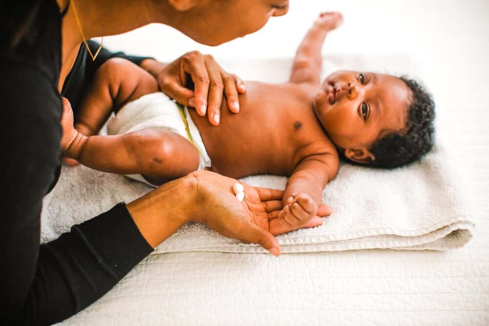Bébé allongé sur une serviette pendant que sa mère lui applique de la lotion pour le corps.