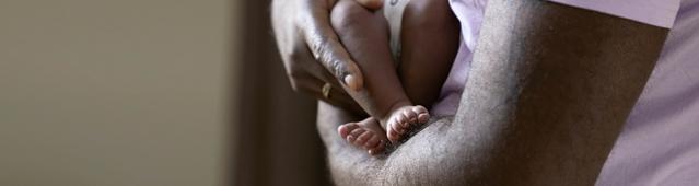 Des jambes de bébé dans les bras d’un parent