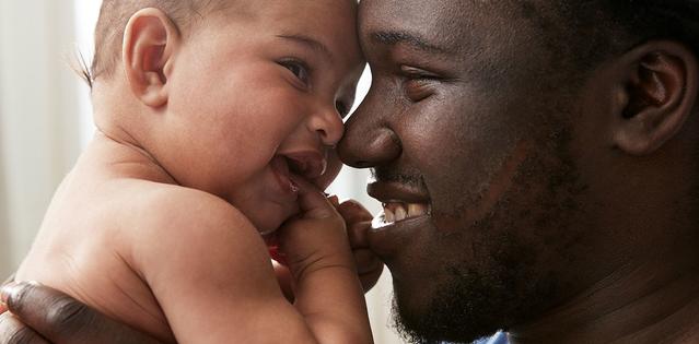 Un papa souriant portant un bébé qui lui sourit