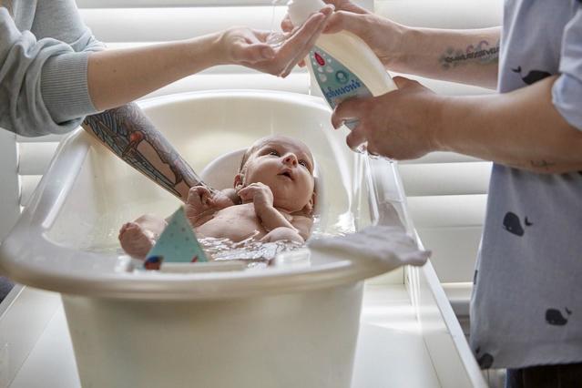 Bain d'un nouveau-né avec le nettoyant et shampoing pour nouveau-nés Johnson’s® DouxCoton®