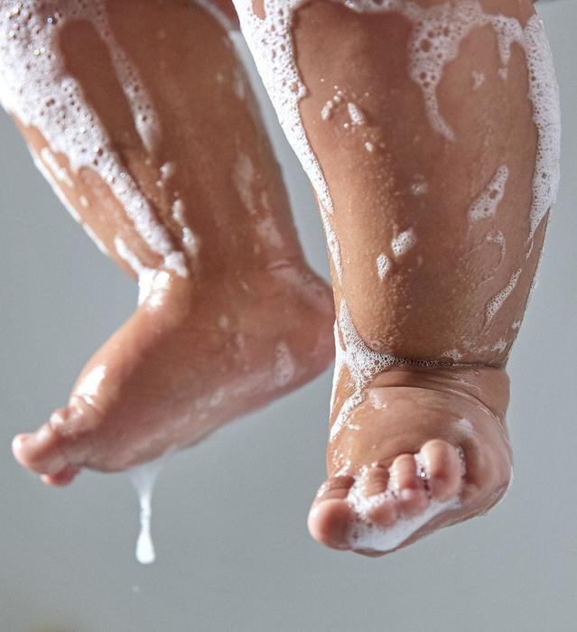 Petites jambes de bébé recouvertes de savon sans une baignoire