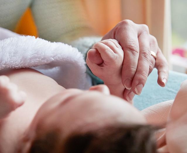 Newborn holding onto adult thumb